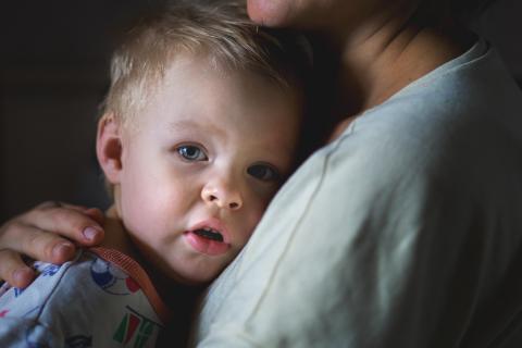 Young boy nestled into an adults chest in a hug