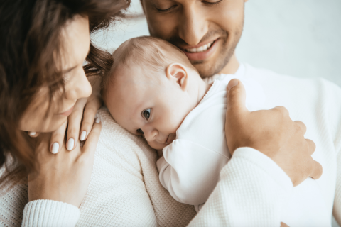 cropped view of happy man holding baby next to a smiling woman