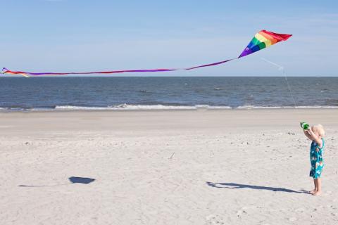 Child flying a kite on a beach