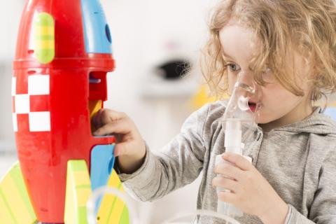A child with cystic fibrosis uses a nebuliser while playing