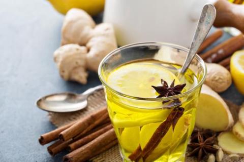 Nautral remedies including ginger and lemon, next to a yellow drink in a glass