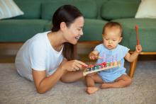 Mother and baby playing with a xylophone on the floor