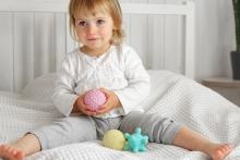 Young child playing with pastel coloured toys on a bed