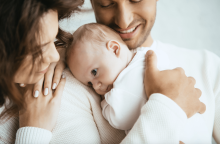 cropped view of happy man holding baby next to a smiling woman