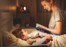 Mother reading to her child in bed