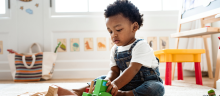 Little boy playing with a toy wooden train set