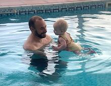 A dad teaching his baby to swim for the first time