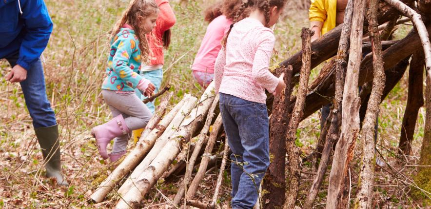 Family with children building a den in the forest out of logs and sticks