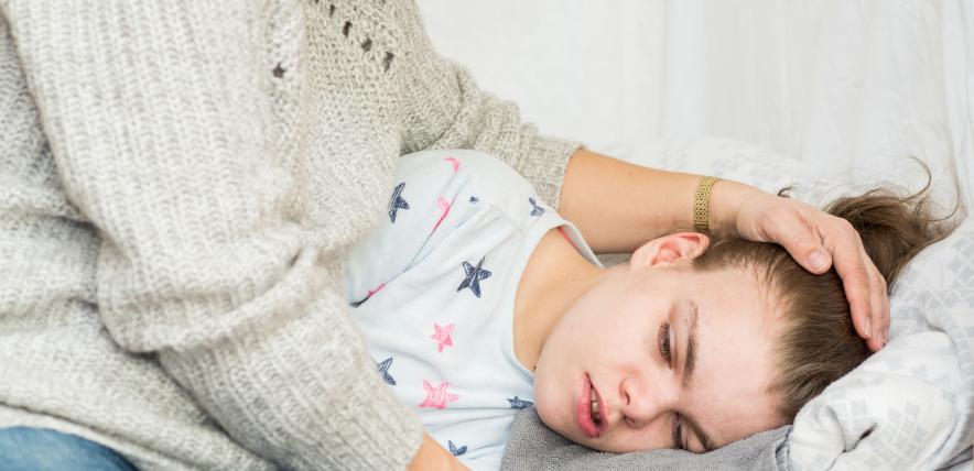 Child lying in bed being cared for