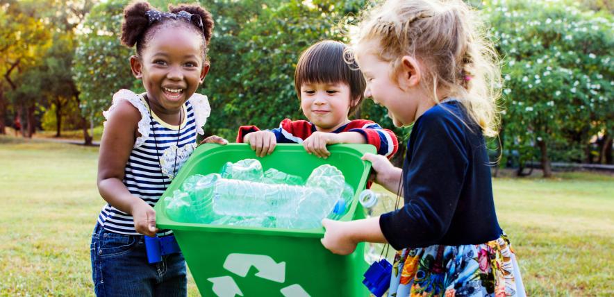 Three children holding a recycling bin