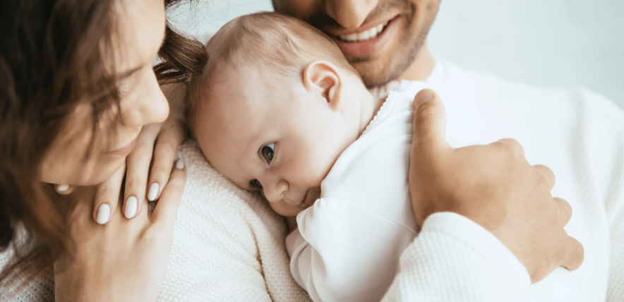 cropped view of happy man holding baby next to a smiling woman