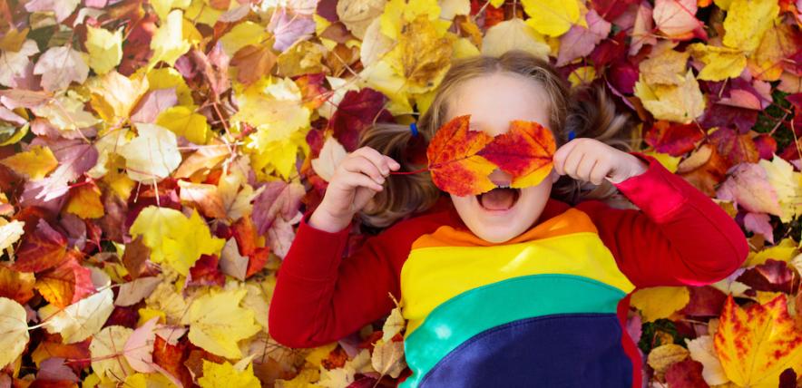 Child playing in autumn leaves