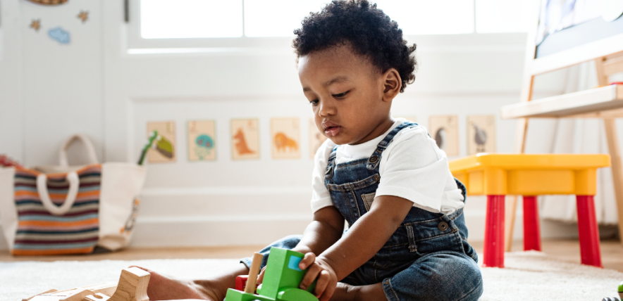 Little boy playing with a toy wooden train set