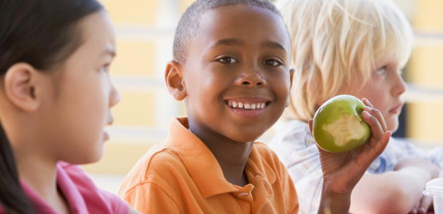 Little boy eating an apple at lunchtime