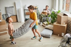 Portrait of two boys building pillow fort in room with boxes while family moving in to new house, copy space